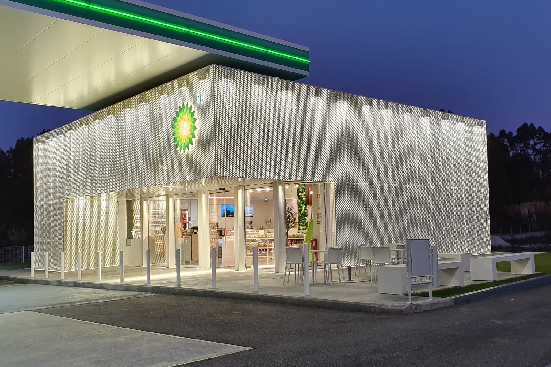 The BP station at blue hour, the perforated metal box alight from within and the green blade of the canopy running across above it.