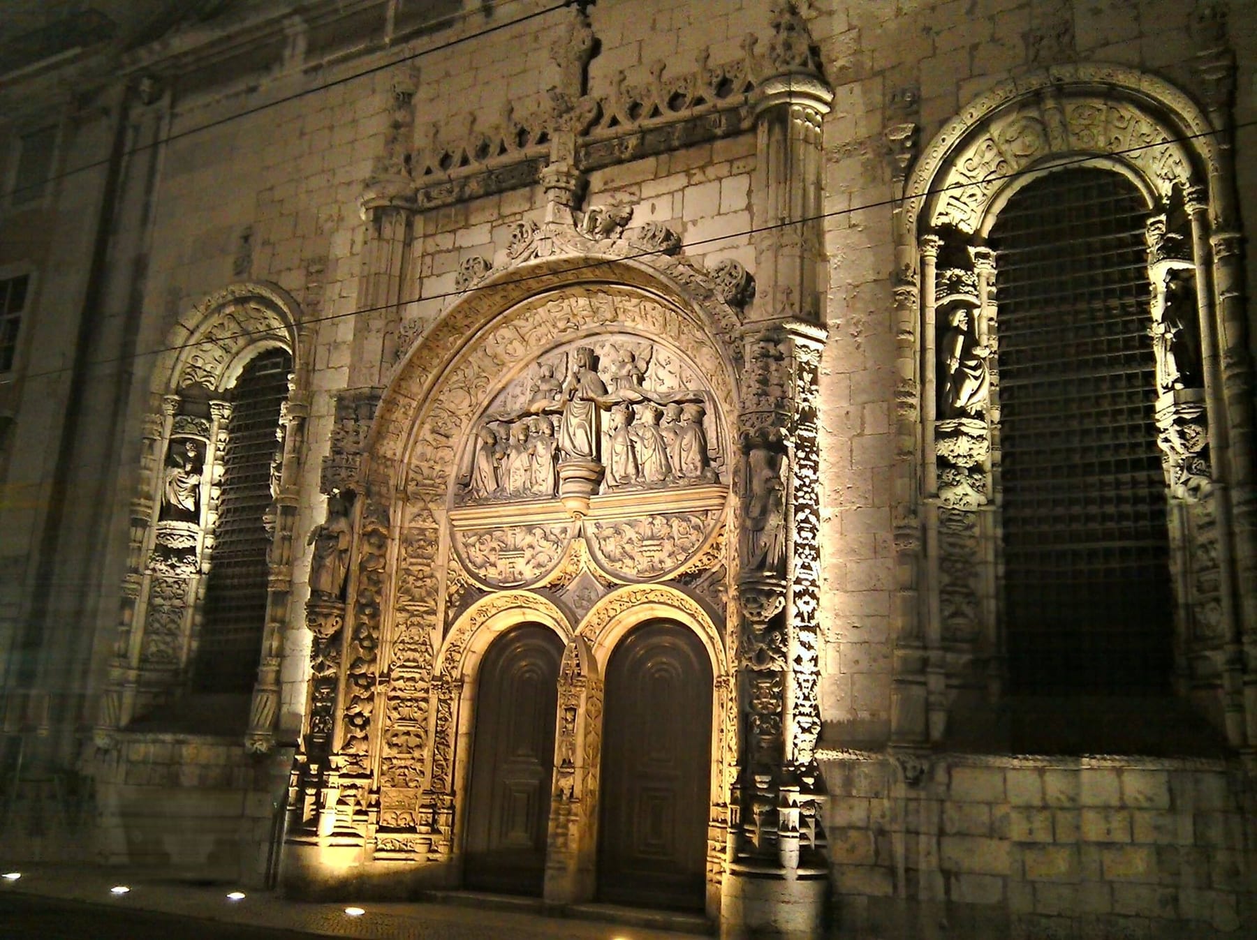 The Manueline portal of the Conceição Velha church washed from below, the carved stone gaining relief and the side bays carried with it.