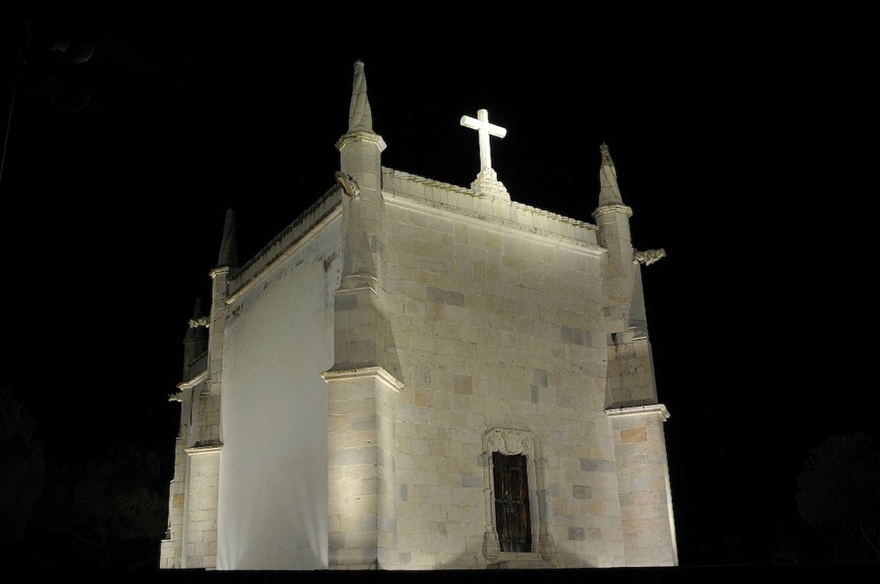 The church of São Jerónimo lit at night, the pinnacles and the cross standing clear of the dark and the stone taking light from below.