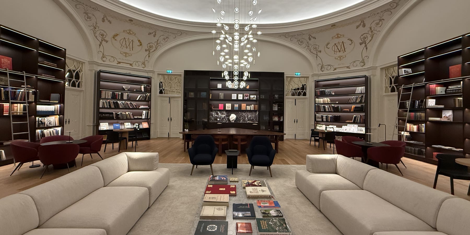 The MACAM library under its cove-lit dome, the dark timber shelving run through with integrated linear light.