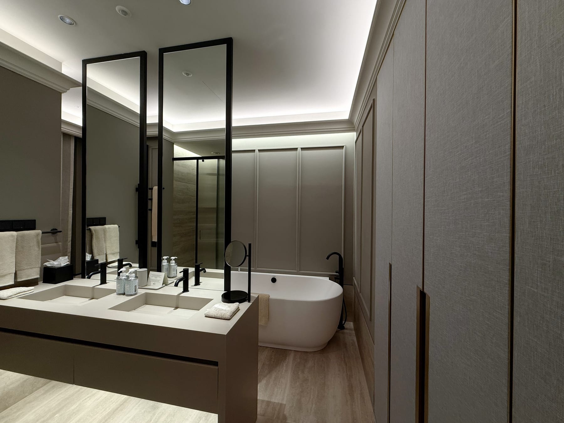 A suite bathroom, a cove of light running the whole ceiling, tall mirrors and a freestanding tub.