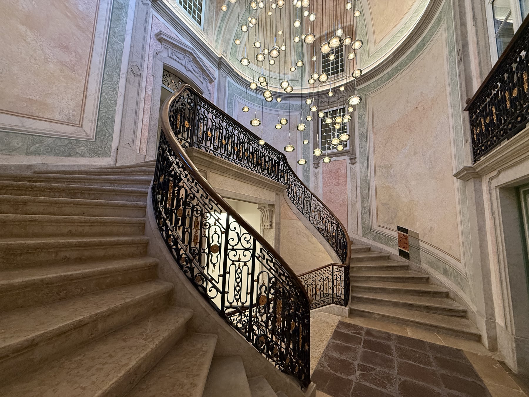 The state staircase of the palace, a cascade of crystal globes falling from the dome over the wrought-iron balustrade.