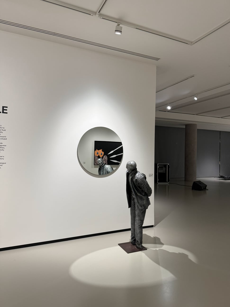 The temporary gallery, the sculpture standing in its own pool of light on the floor and a circular opening cut through the wall returning the painting in the room beyond.
