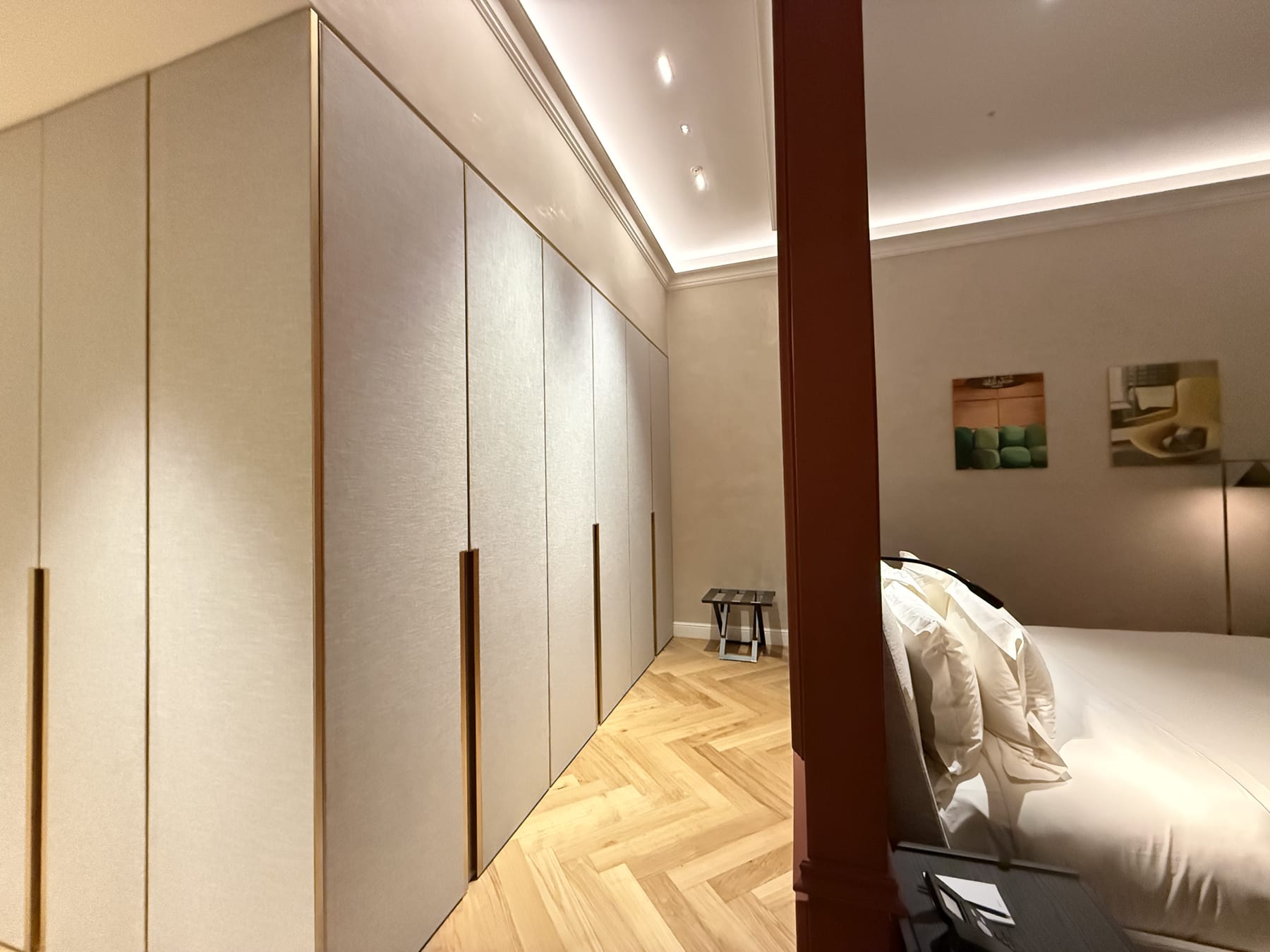 The same room from the other side, the wardrobes washed by a cove and the herringbone floor running to the door.