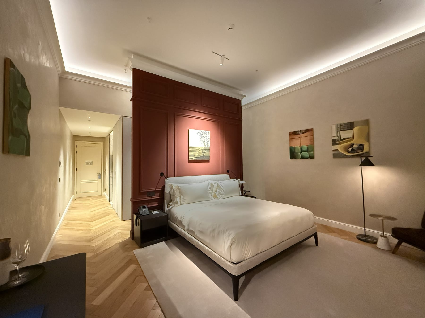 A guest room at the MACAM Hotel, the terracotta panelled wall behind the bed and a cove of light running the ceiling.