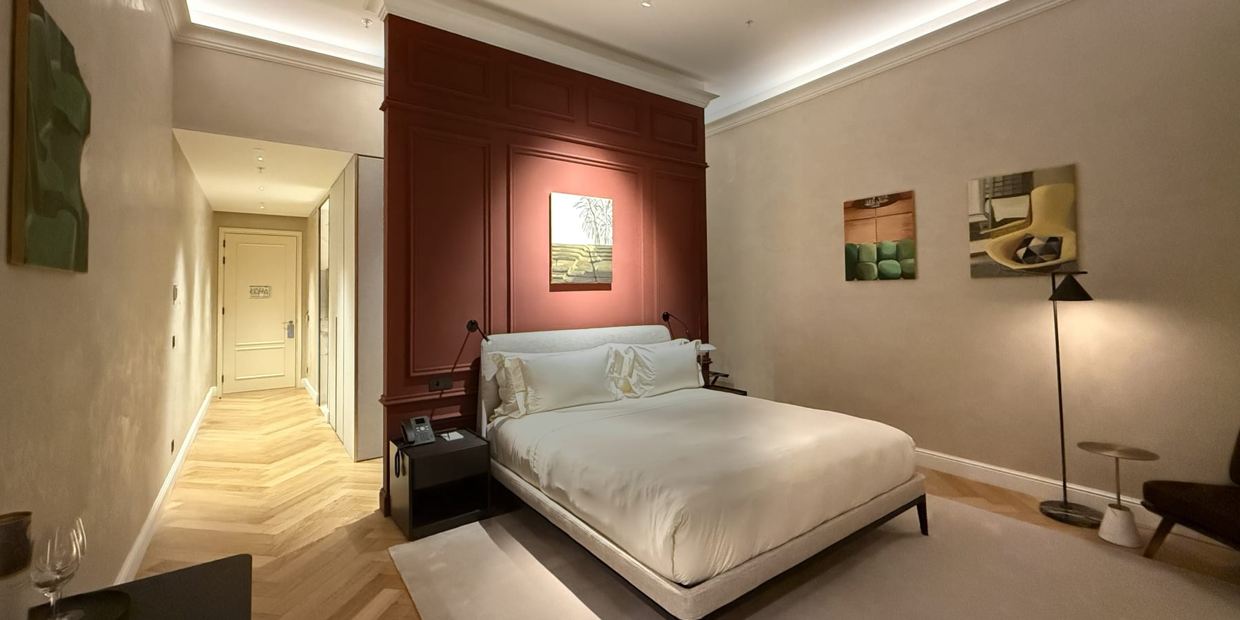 A guest room at the MACAM Hotel, the terracotta panelled wall behind the bed and a cove of light running the ceiling.