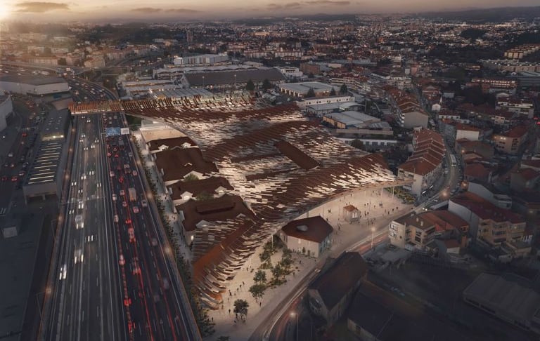Aerial view of Porto's former Campanhã slaughterhouse at dusk, the new roof spreading over the pavilions and the motorway running along the block.