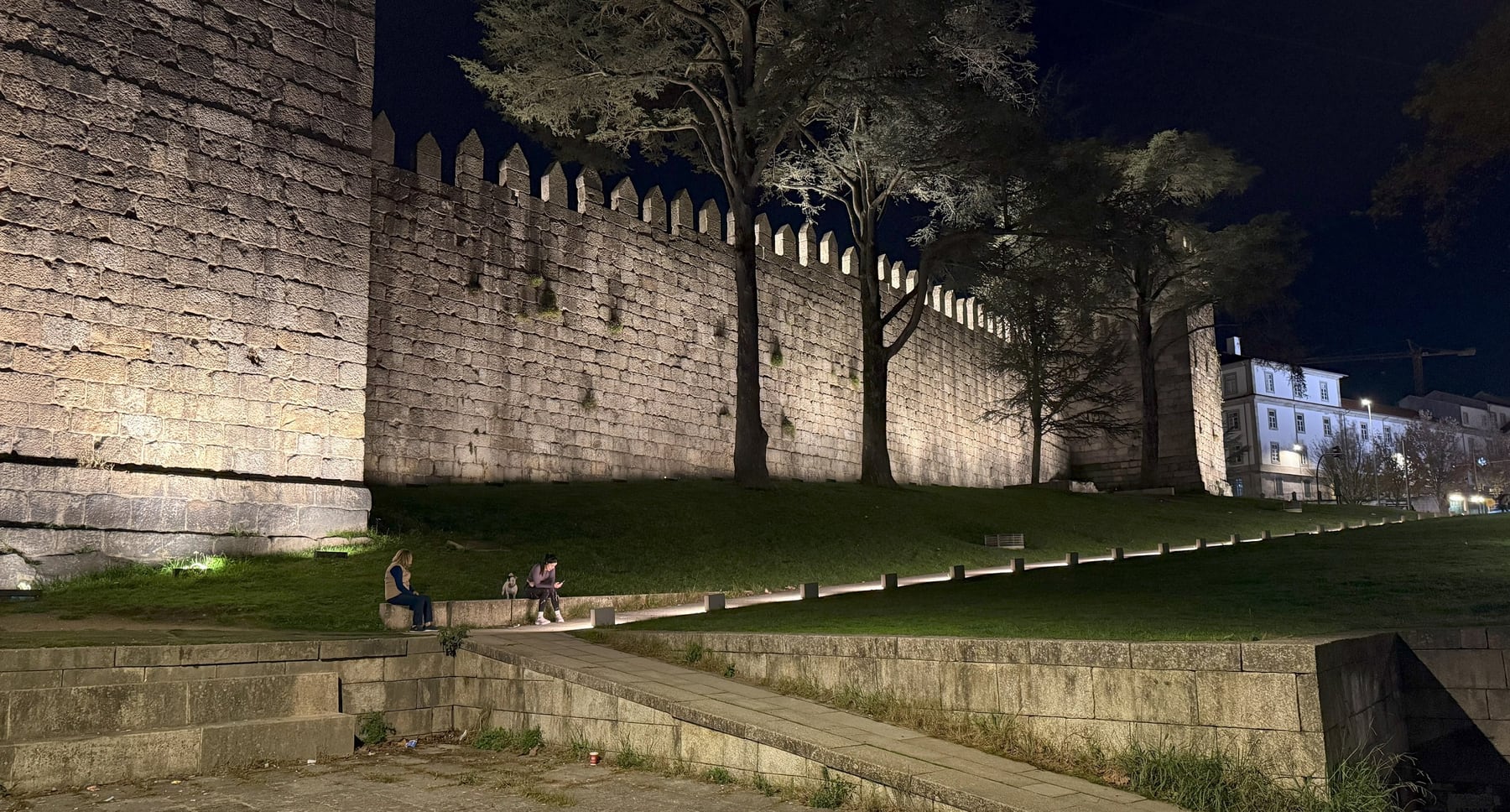 The Fernandine Wall at lawn level, a grazing light picking up the granite and the run of merlons carried the whole width.