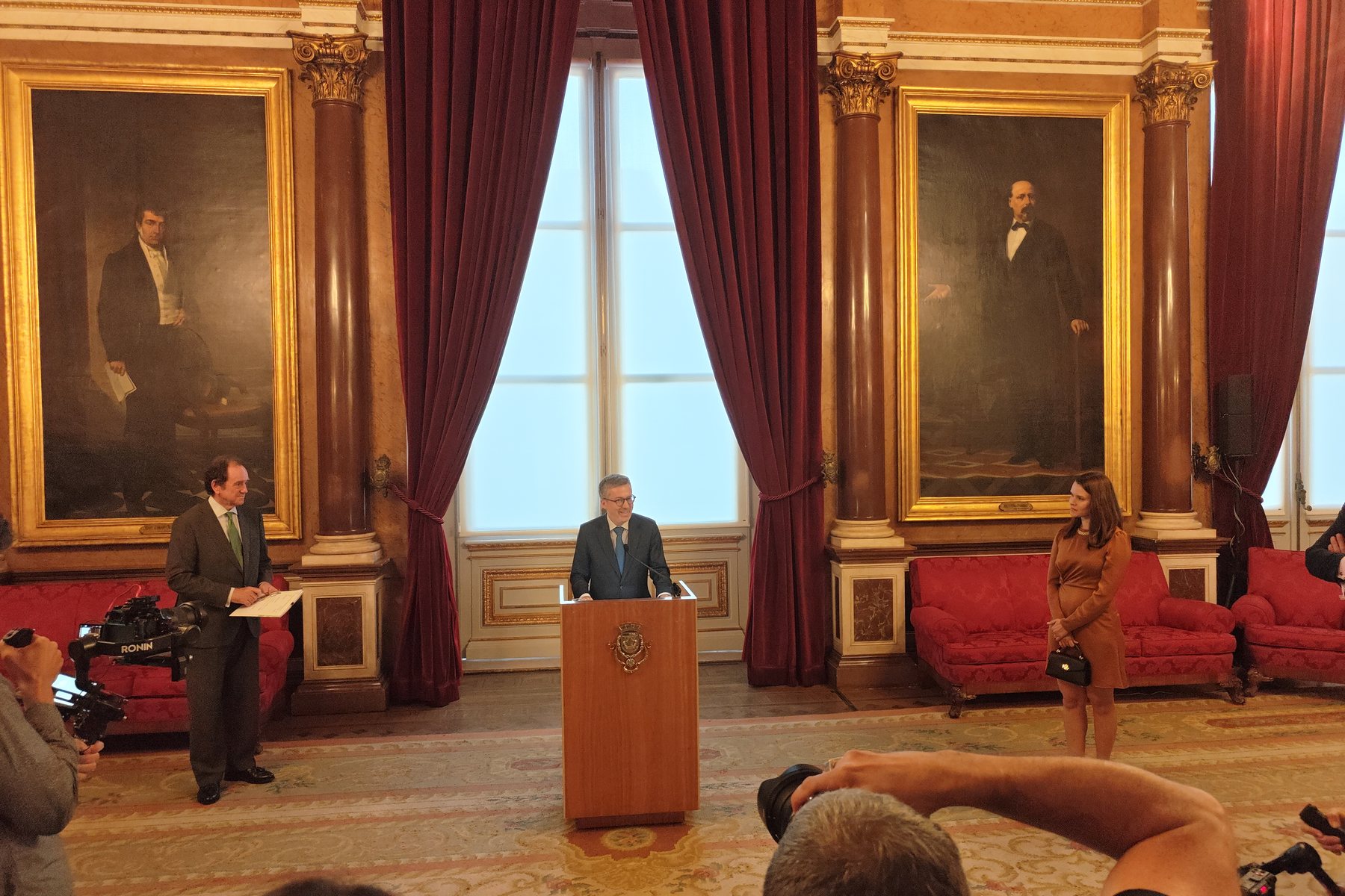 Carlos Moedas habla en la inauguración, en una sala de los Paços do Concelho, con Diana Delnegro a la derecha.