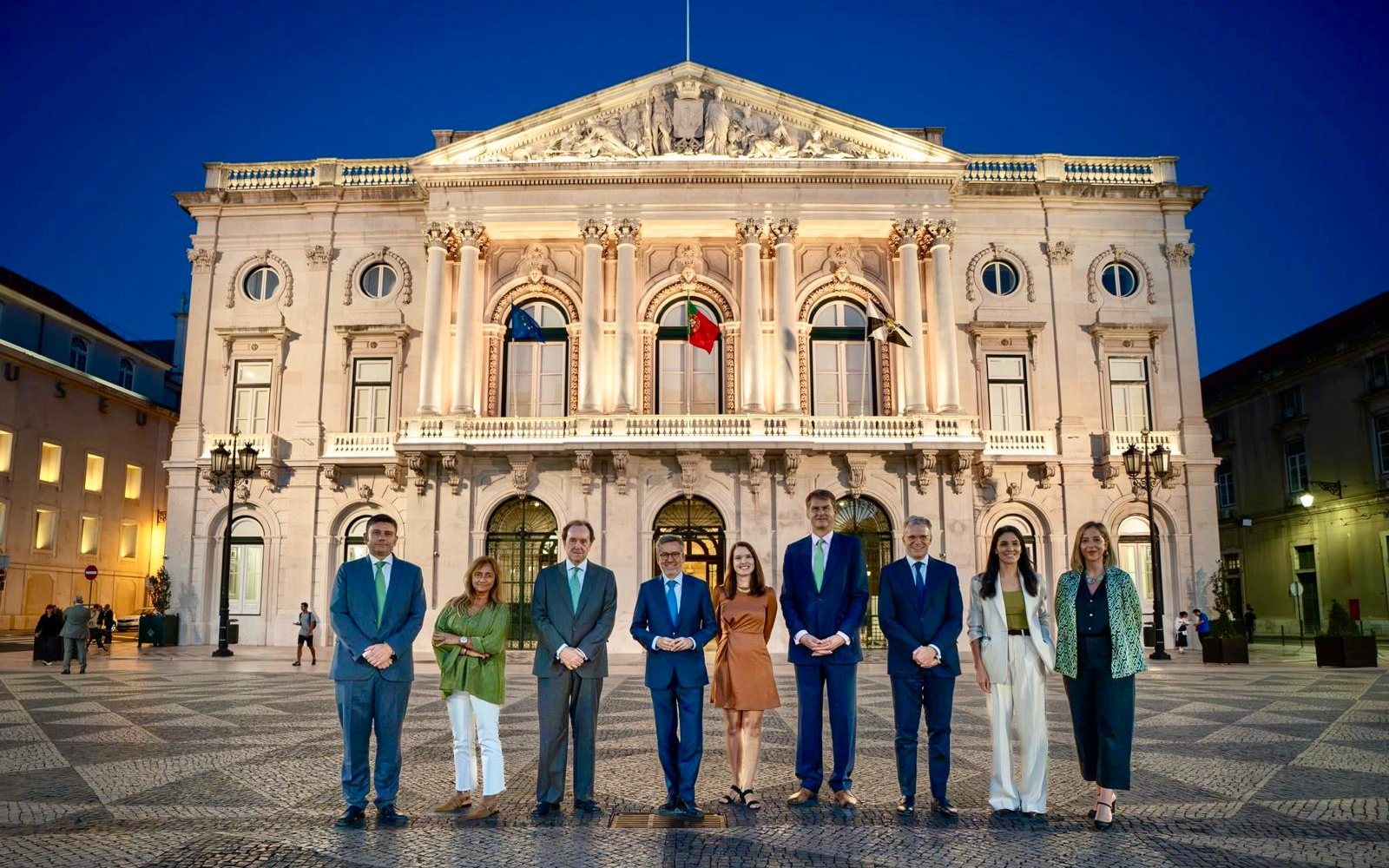Diana Delnegro entre el alcalde de Lisboa, Carlos Moedas, y Hugh Elliott, de Iberdrola, con Jaime Alfonsín, Gonçalo Reis y los demás invitados, ante la fachada iluminada.