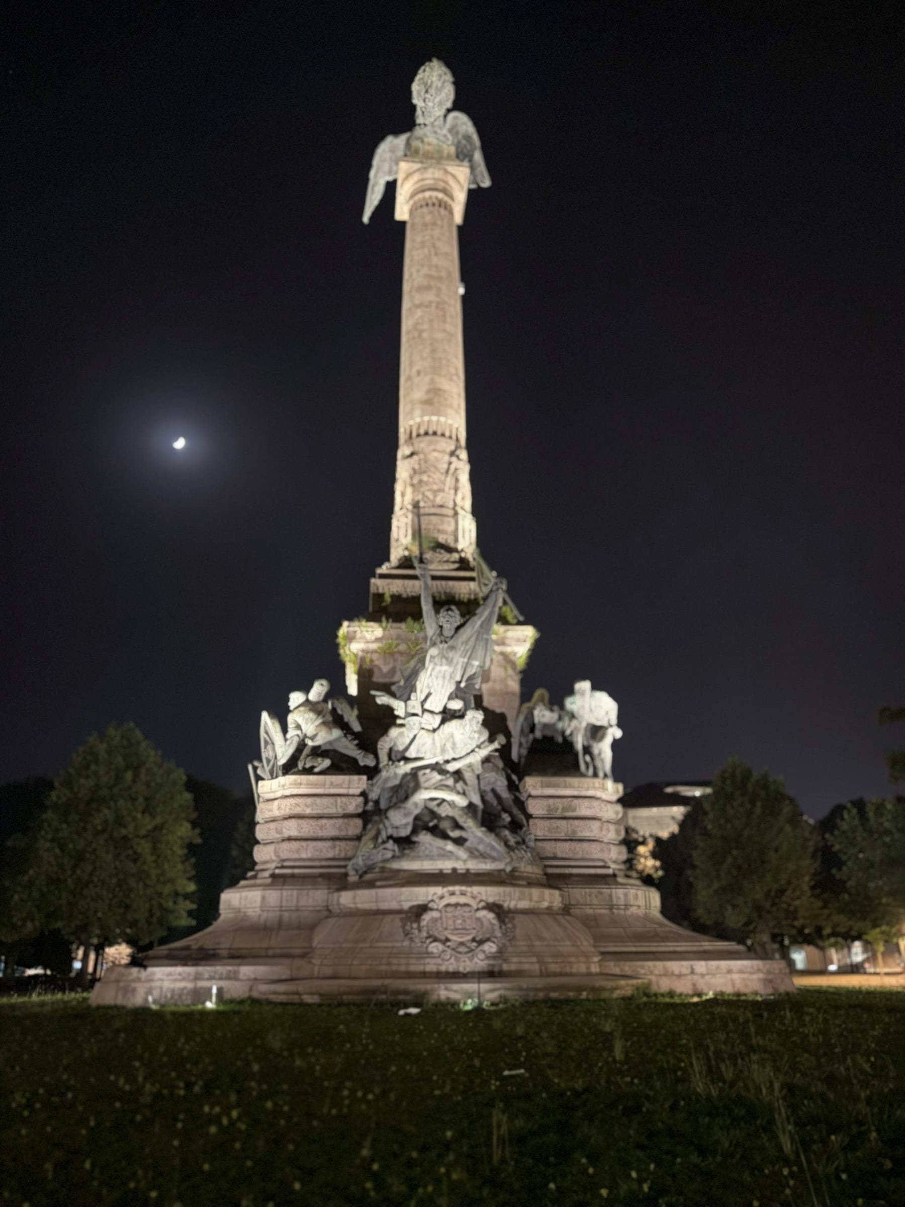 The Monument to the Heroes of the Peninsular War at the centre of the Boavista roundabout, the column washed from below over its full height and the lion at the top cut against the sky.